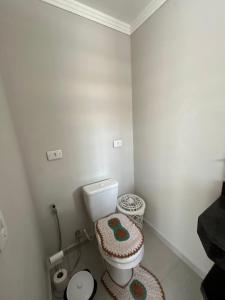 a white bathroom with a toilet and a rug at CASA ESPAÇOSA e CONFORTÁVEL EM PARATY in Paraty