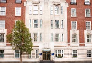 a building with a tree in front of it at Thistle London Park Lane in London