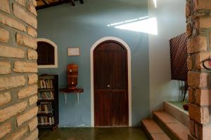 a hallway with a wooden door and a brick wall at Hospedagem do Sítio in Lençóis