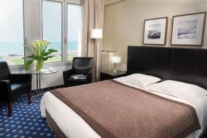 a hotel room with a bed and a large window at Hotel Aguado in Dieppe
