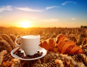a cup of coffee and a croissant in a field at casa lontana only genius in Borgofranco dʼIvrea +2 photos