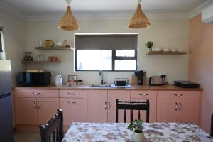 a kitchen with pink cabinets and a table and a window at Ongersfontein gasteplaas in Richmond +31 photos