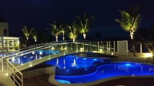 a swimming pool at night with a bridge over it at Kaakupe Praia Hotel in Guaratuba