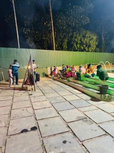 a group of people sitting on a green bench at Rivera Holiday Home in Vythiri