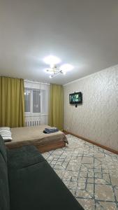 a bedroom with a bed and a tv on a wall at 5 минут Астана Аэропорт in Prigorodnyy