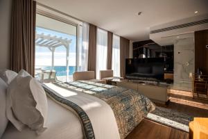 a bedroom with a large bed and a large window at Empire Beach Resort ADULTS ONLY in Dhërmi