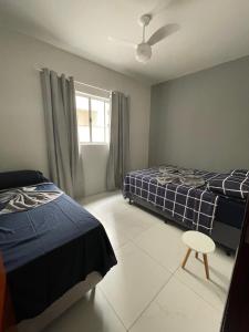a bedroom with two beds and a ceiling fan at Achadinho no Coração de Aparecida 2 in Aparecida