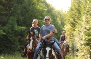 two girls riding on horses on a path at Above Mustang Condos in Mackinac Island +8 photos