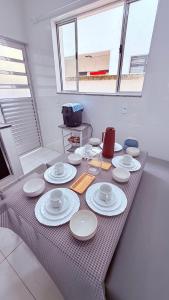 a table with white plates and cups on it at Achadinho no Coração de Aparecida 2 in Aparecida