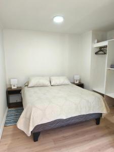 a white bedroom with a bed and two night stands at Departamento Corcovado in Puerto Montt