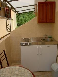 a small kitchen with a sink and a table at Apartmani More in Sveti Stefan