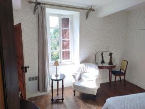 a bedroom with a white chair and a window at Aile de la Maison de Chouliou in Balaguères