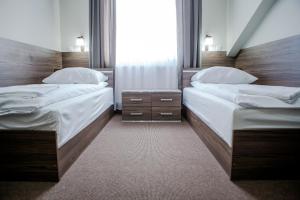 two twin beds in a room with a window at Motel Domowy Gościniec in Łomża
