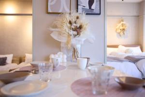 a dining table with glasses and a vase with flowers at Mezon Etowaaru in Nagoya