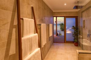 a bathroom with towels hanging on the wall at Hurawalhi Island Resort in Kuredu