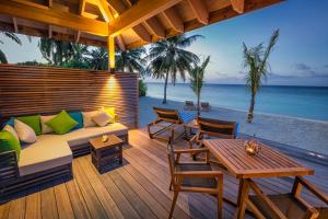 a patio with a couch and a table on the beach at Hurawalhi Island Resort in Kuredu