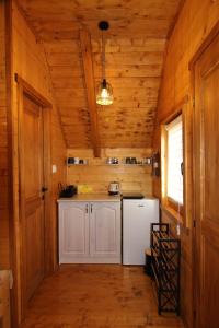a kitchen with a white refrigerator and wooden walls at Etno Lug - Village in Bogetići