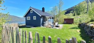 a small blue house in a yard with a fence at Nordfjordcabins BLUE in Utvik