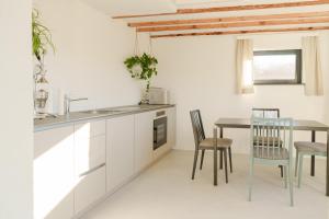 a kitchen with white cabinets and a table and chairs at Almhaus Kloster 38 in Kloster