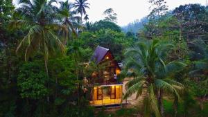 a house in the middle of a forest with palm trees at Rainforest Royal Heritage in Deniyaya