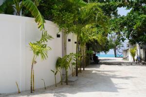 a white wall with palm trees on a beach at Sea Tides Dhangethi in Dhangethi