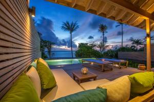 a patio with a couch and a table at Hurawalhi Island Resort in Kuredu