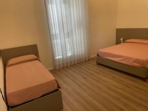 two beds in a small room with a window at Alsama in Canicattì