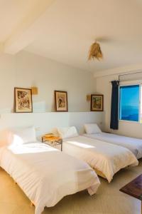 two beds in a room with a window at Olas Surf Camp in Imsouane
