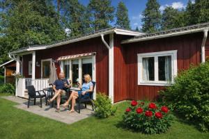 two people sitting at a table outside of a red house at Jojos Lodge in Bräcke