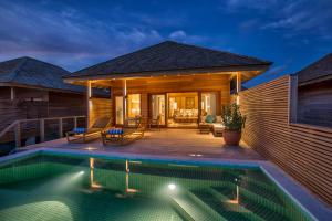 a villa with a swimming pool and a house at Hurawalhi Island Resort in Kuredu