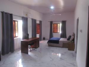 a bedroom with a bed and a desk and windows at Rams Lodge in Accra