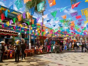 un gruppo di persone che camminano in un mercato con delle bandiere di Hotel Nelson a Tijuana