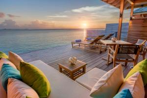 a deck with chairs and a table and the ocean at Hurawalhi Island Resort in Kuredu