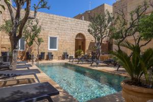 a pool with chairs and trees in a courtyard at Palazzo Pisani & Spa Malta in Żabbar