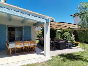 a pergola on a patio with a table and chairs at Villa les volets bleus in Le Grau-dʼAgde
