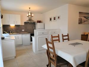 a kitchen with white cabinets and a table and chairs at Villa les volets bleus in Le Grau-dʼAgde