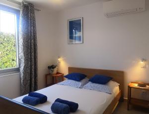 a bedroom with a bed with blue pillows and a window at Villa les volets bleus in Le Grau-dʼAgde