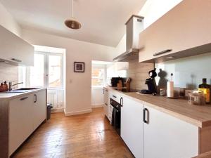 a kitchen with white cabinets and a wooden floor at Maison atypique - Au coeur de la vieille ville in Le Puy-en-Velay