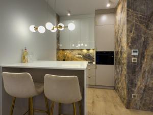 a kitchen with two bar stools and a counter at VIDOK Apartament Olsztyn Premium 204 in Olsztyn