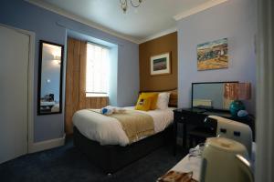 a bedroom with a bed with a desk and a window at Arosfa Harbourside Aberaeron in Aberaeron