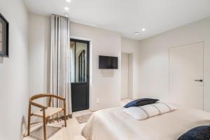 a white bedroom with a bed and a chair at De Kompanie in Alken