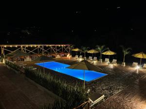 a swimming pool with umbrellas on the beach at night at Glamping Del Río by Trip Monkey in San Gil