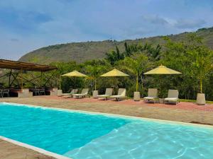 a swimming pool with lounge chairs and umbrellas at Glamping Del Río by Trip Monkey in San Gil