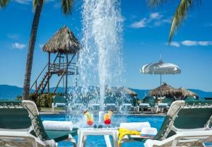 a fountain in a swimming pool with chairs and a table at Ocean Breeze Nuevo Vallarta in Nuevo Vallarta