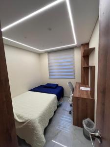 a bedroom with a bed and a desk and a window at El lujo y la comodidad in Zipaquirá