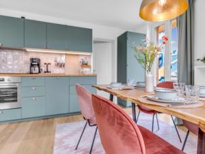a kitchen with blue cabinets and a wooden table with chairs at Haus am Seeufer mit Badestelle in 200m, große Sonnenterrasse, umzäunter Garten, Hunde willkommen in Rheinsberg