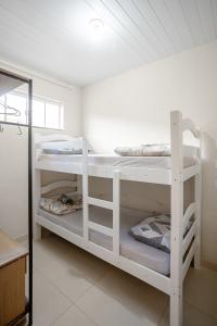 a room with two white bunk beds in it at Casa Aconchego da Bisa - perto do Estádio do Operário! in Ponta Grossa