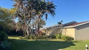 a house with a palm tree in a yard at Aloha Sands Scottburgh in Scottburgh