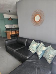 a black leather couch in a living room with a mirror at Depto arlegui centro in Viña del Mar