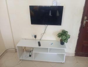 a flat screen tv on a wall with a white desk at Nest Apartment Diani in Diani Beach